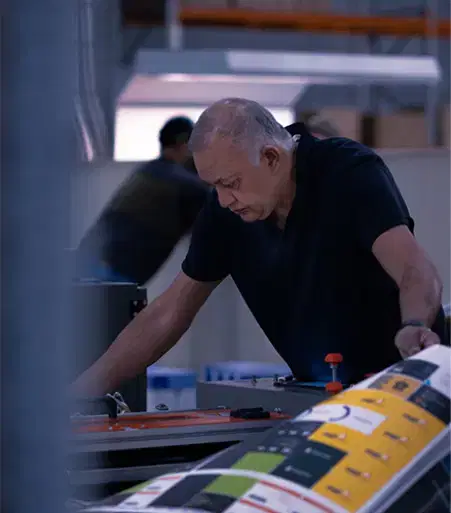 Service-home-6 Older man in a black shirt focused on operating a large printing machine in a dimly lit industrial workspace." Let me know if you want it adjusted or need alt text for more images!